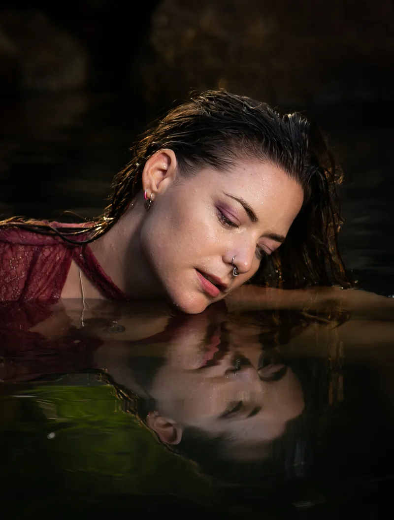 Woman resting in water, her reflection visible below