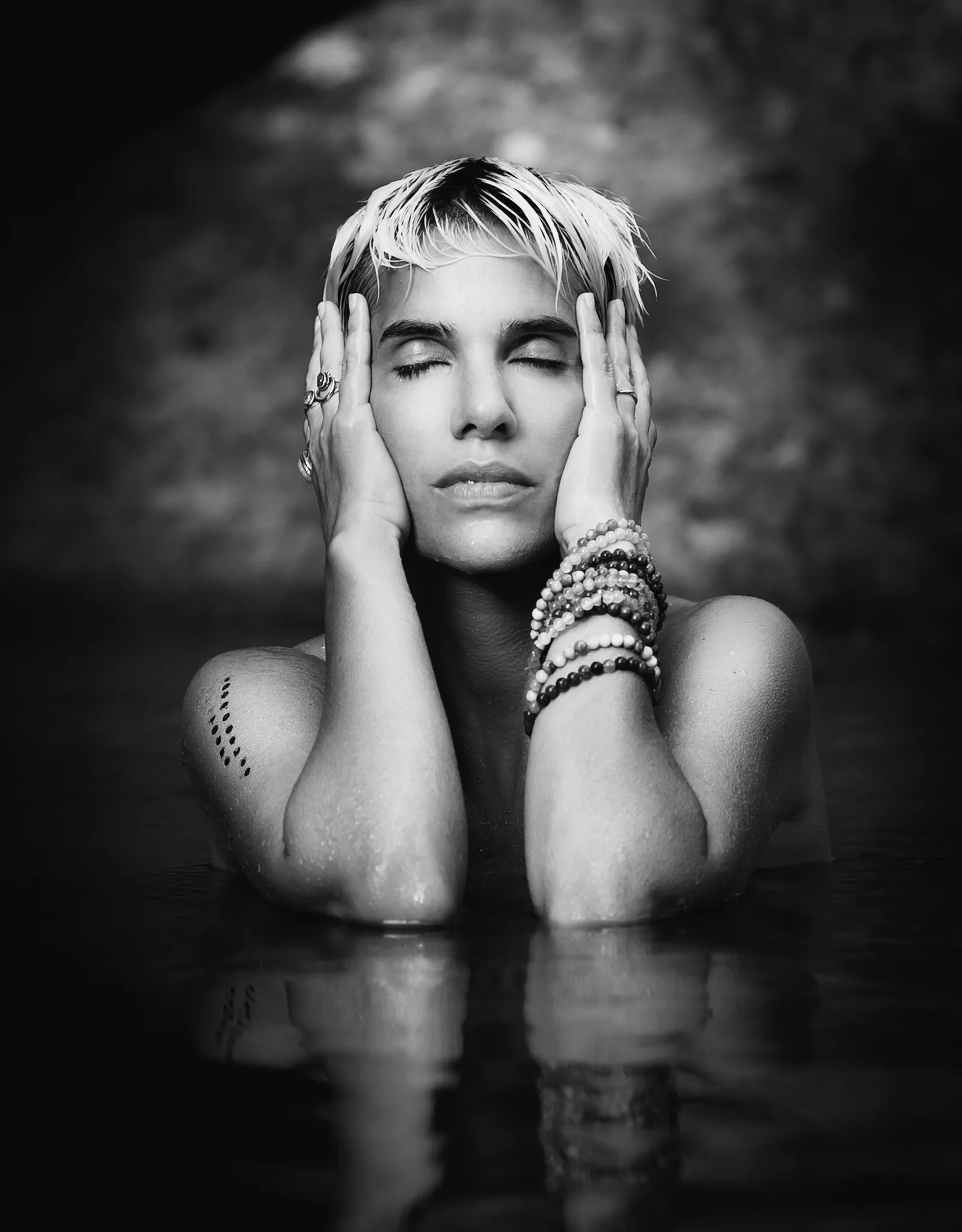Black and white portrait of a person resting their face in their hands in water
