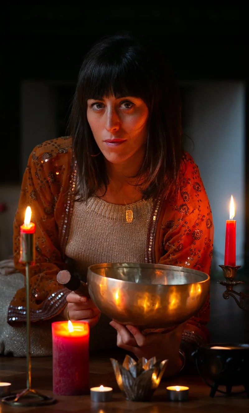 Woman holding a singing bowl by candlelight