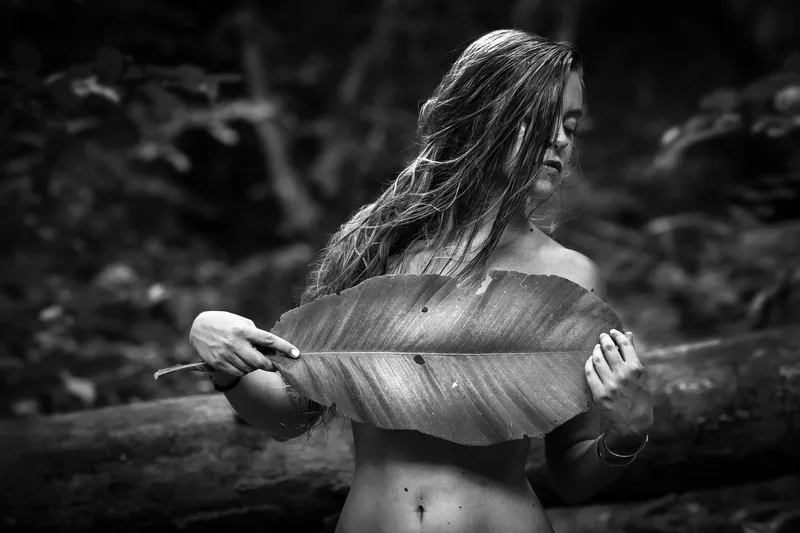 Black and white portrait behind a large leaf